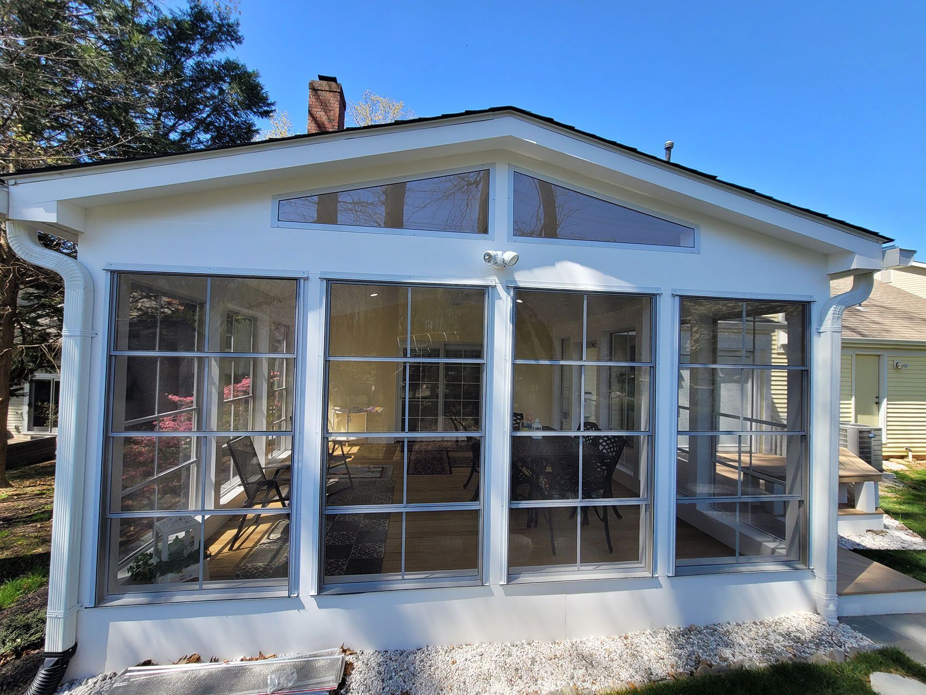 A white house with a screened in porch and a lot of windows.
