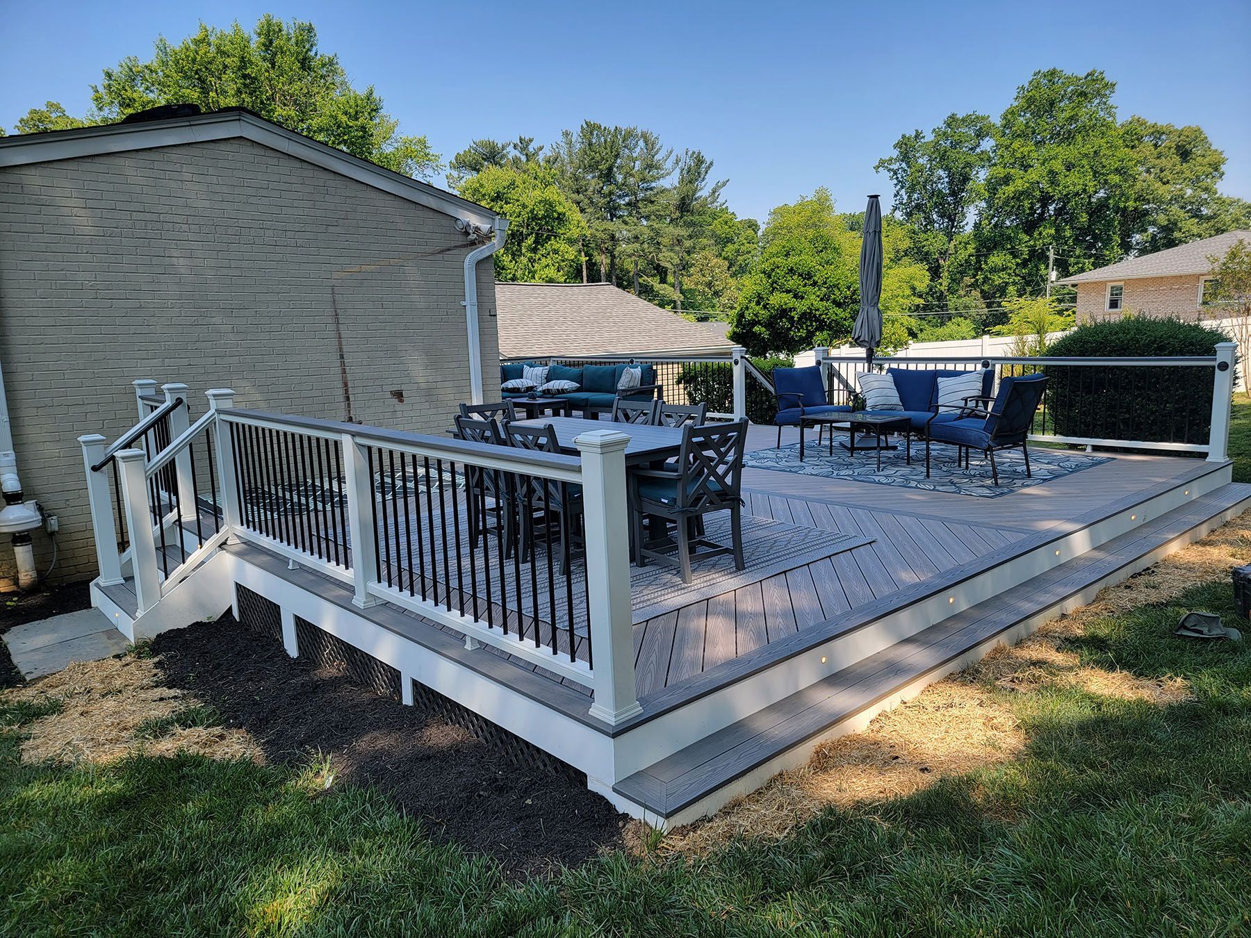 A large wooden deck with a white railing and patio furniture.