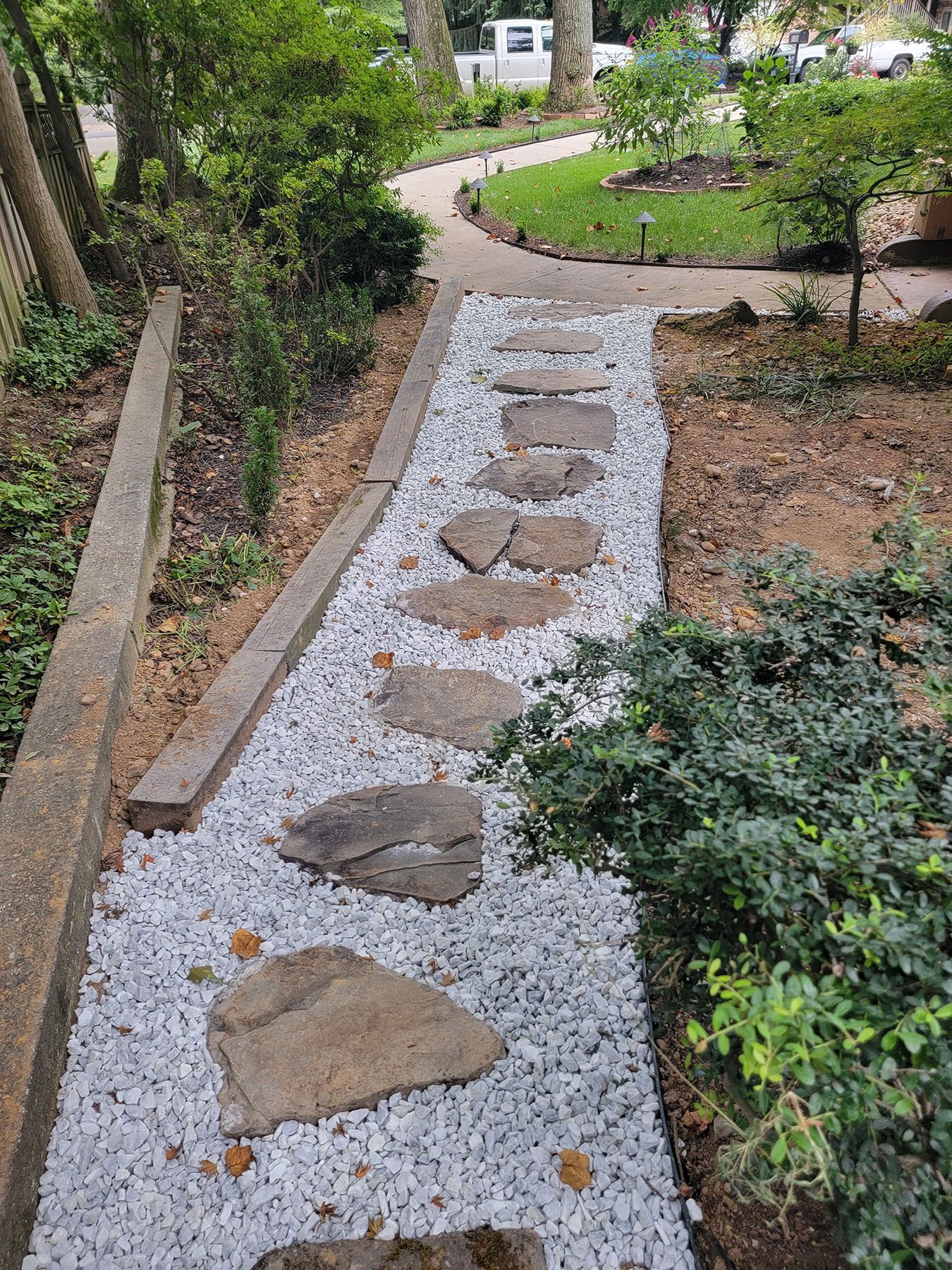 A stone walkway with white gravel and stepping stones in a garden.