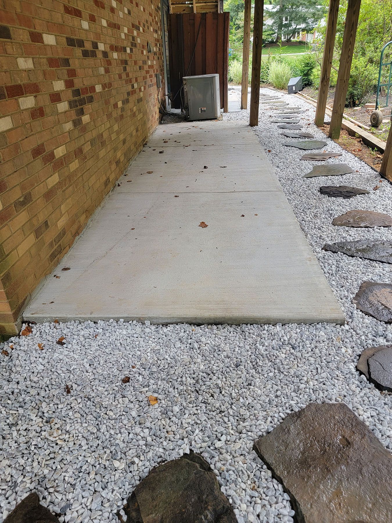 A concrete walkway surrounded by gravel and rocks next to a brick wall.