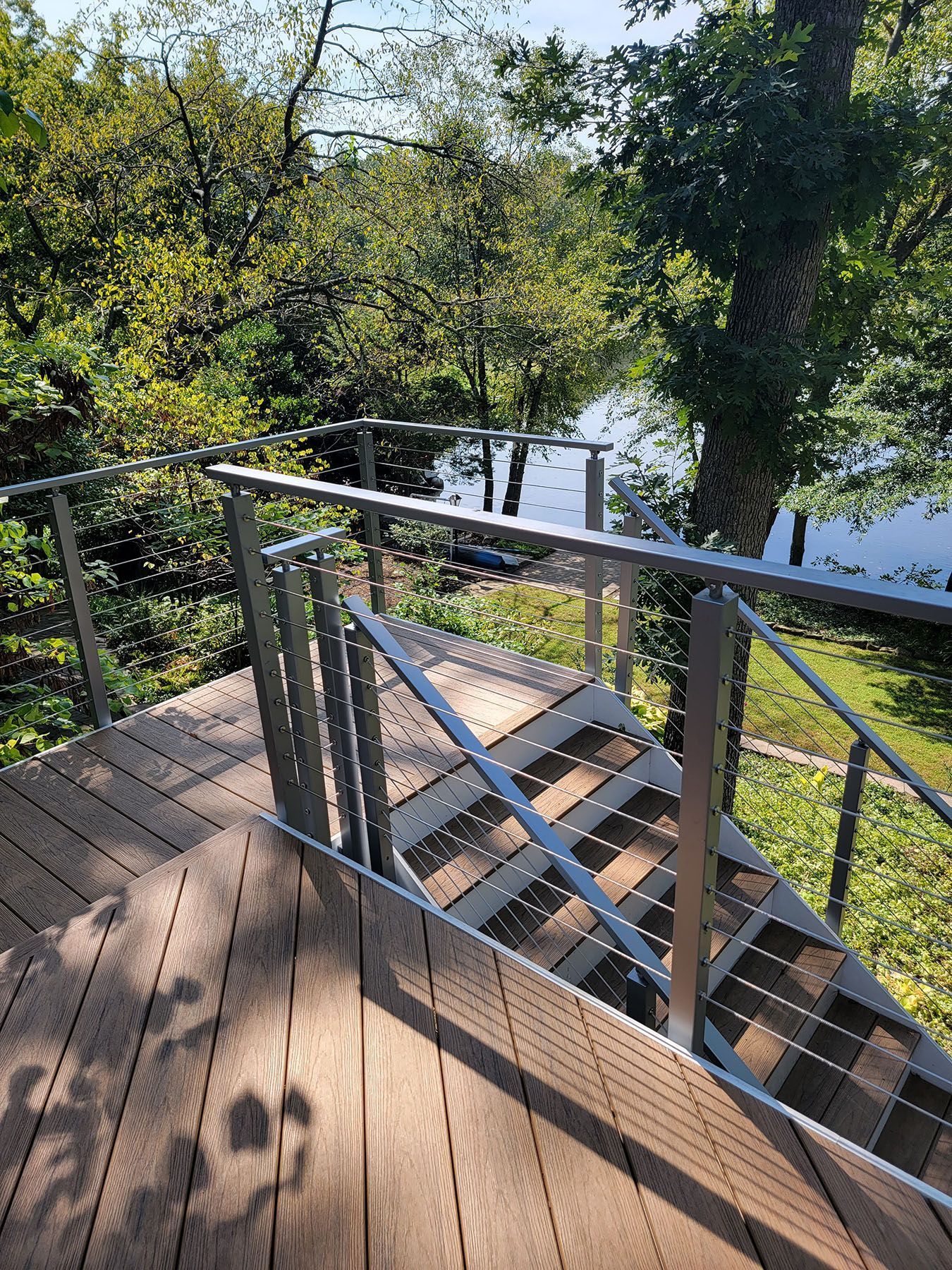 A wooden deck with stairs leading up to a lake surrounded by trees.