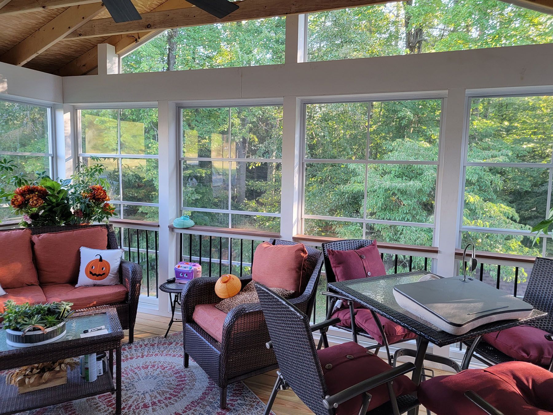 A screened in porch with wicker furniture and a table.