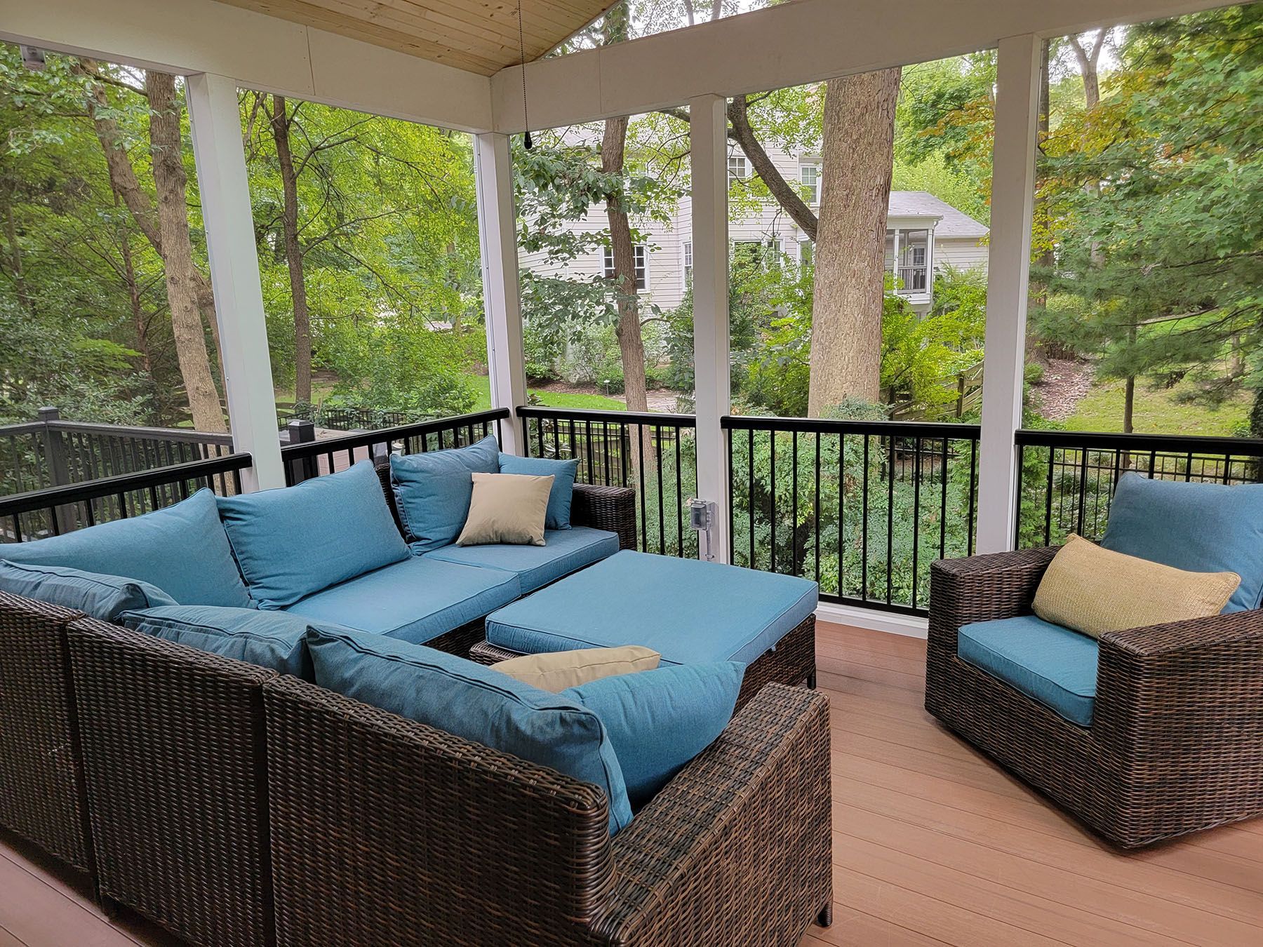 A screened in porch with wicker furniture and blue cushions.