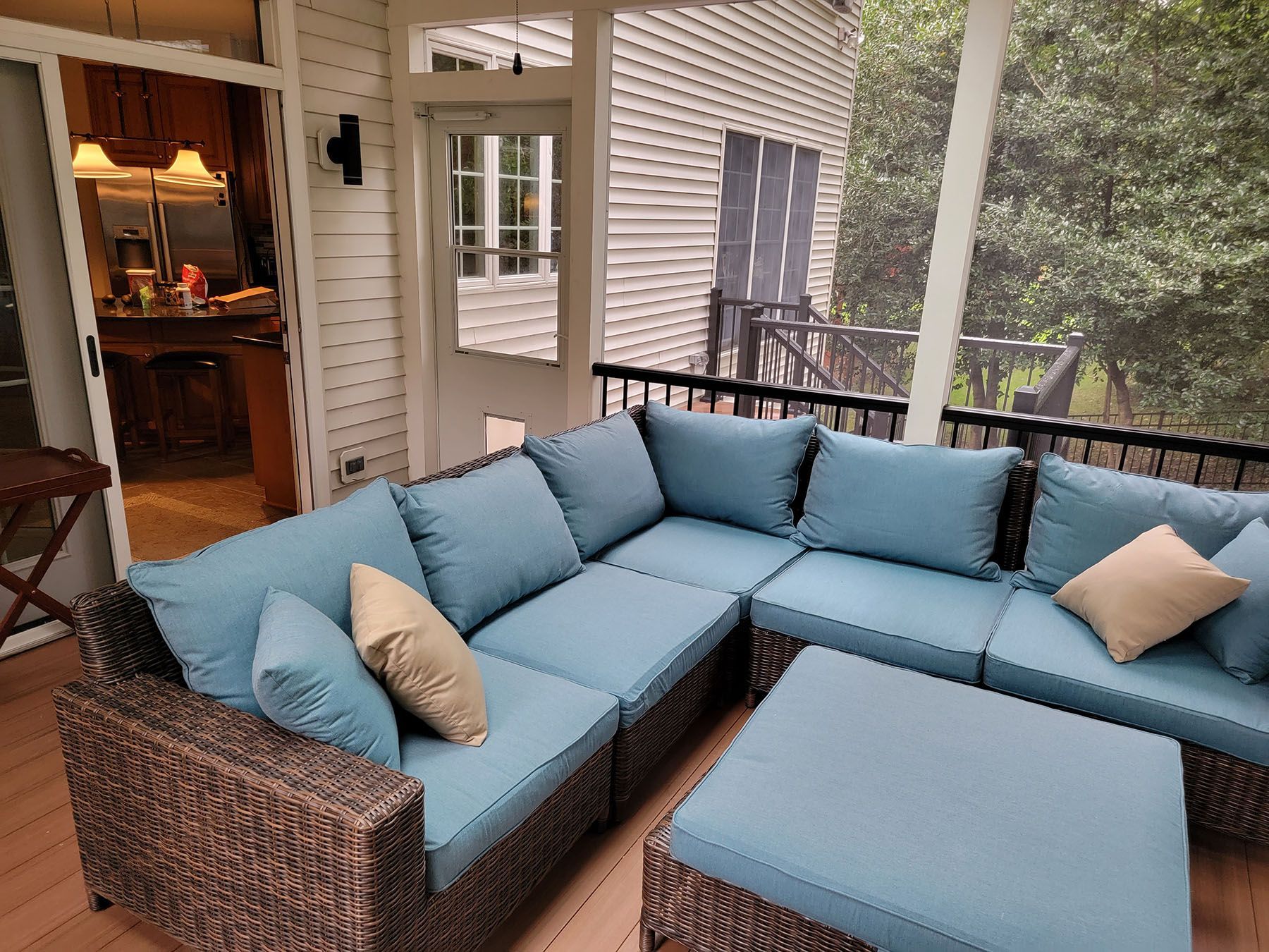 A screened in porch with a sectional couch and ottoman.