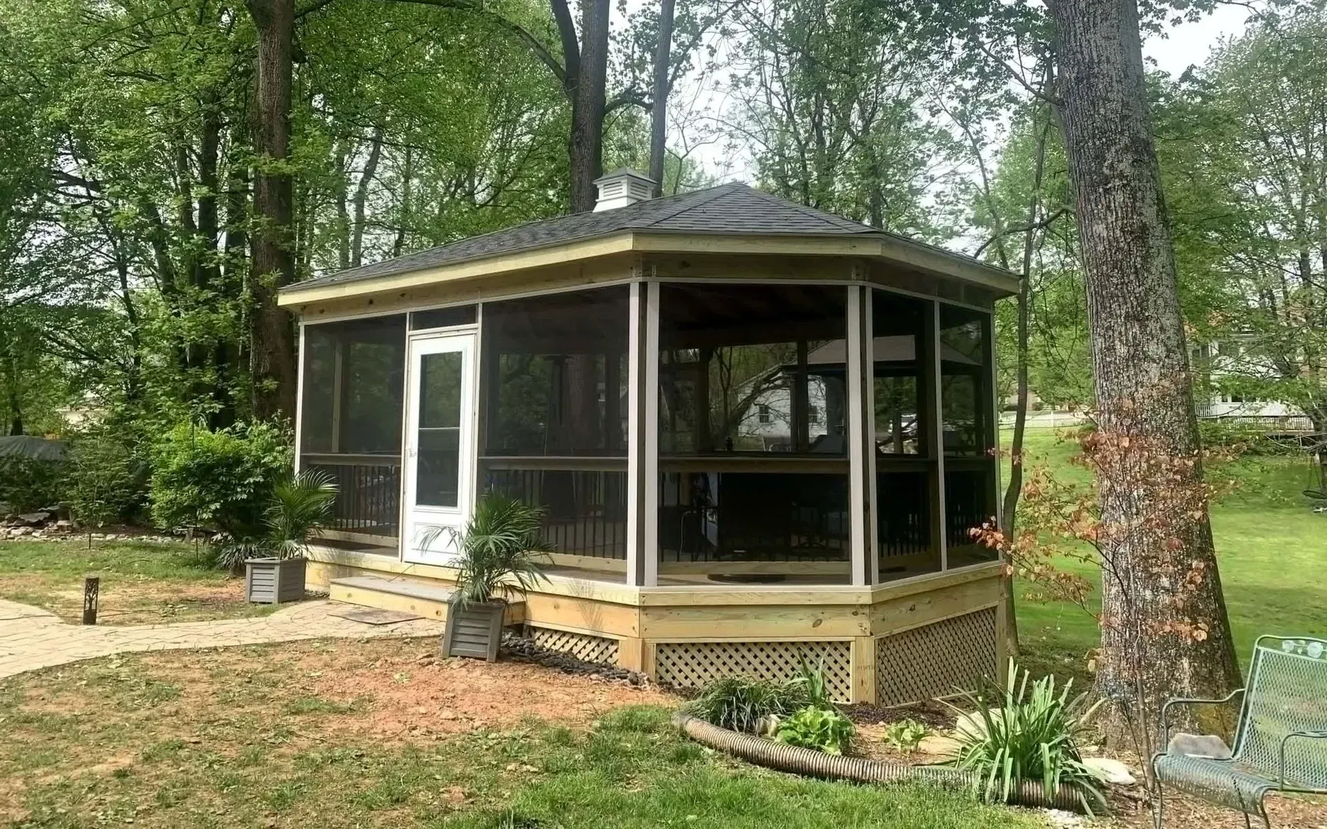 A screened in gazebo is sitting in the middle of a lush green field.