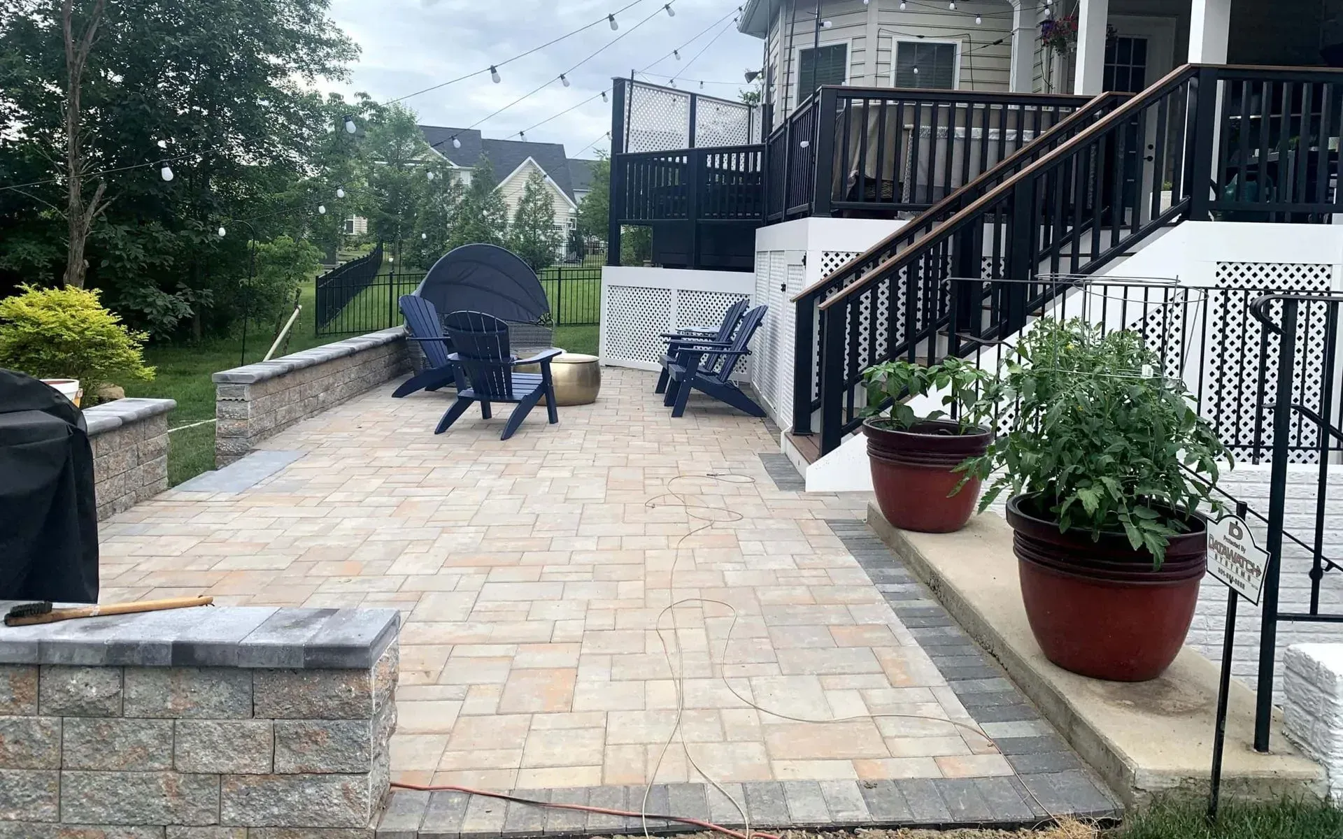 A patio with chairs and a grill in front of a house.