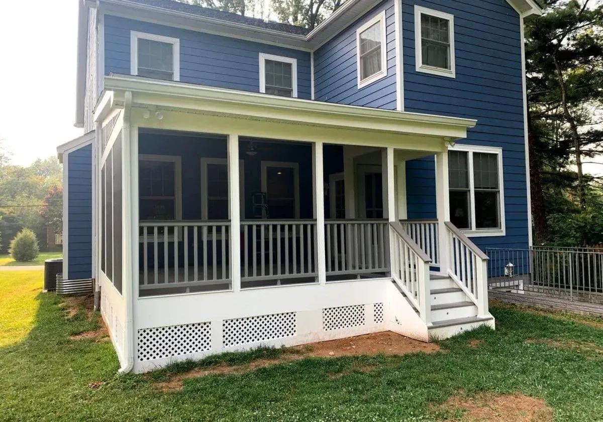 A blue house with a screened in porch and stairs.