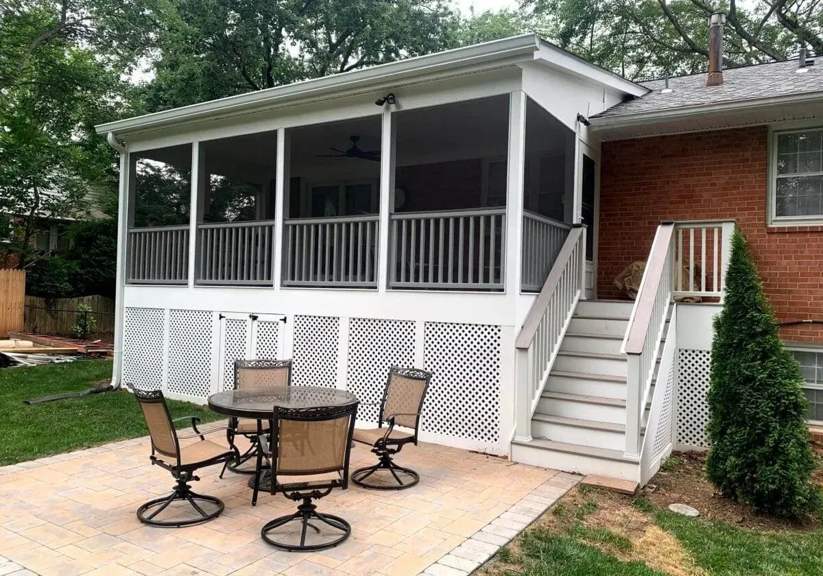 There is a screened in porch with a table and chairs on it.