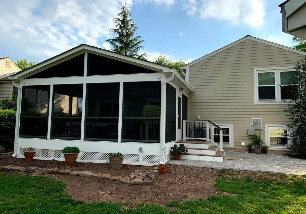 A screened in porch in the backyard of a house
