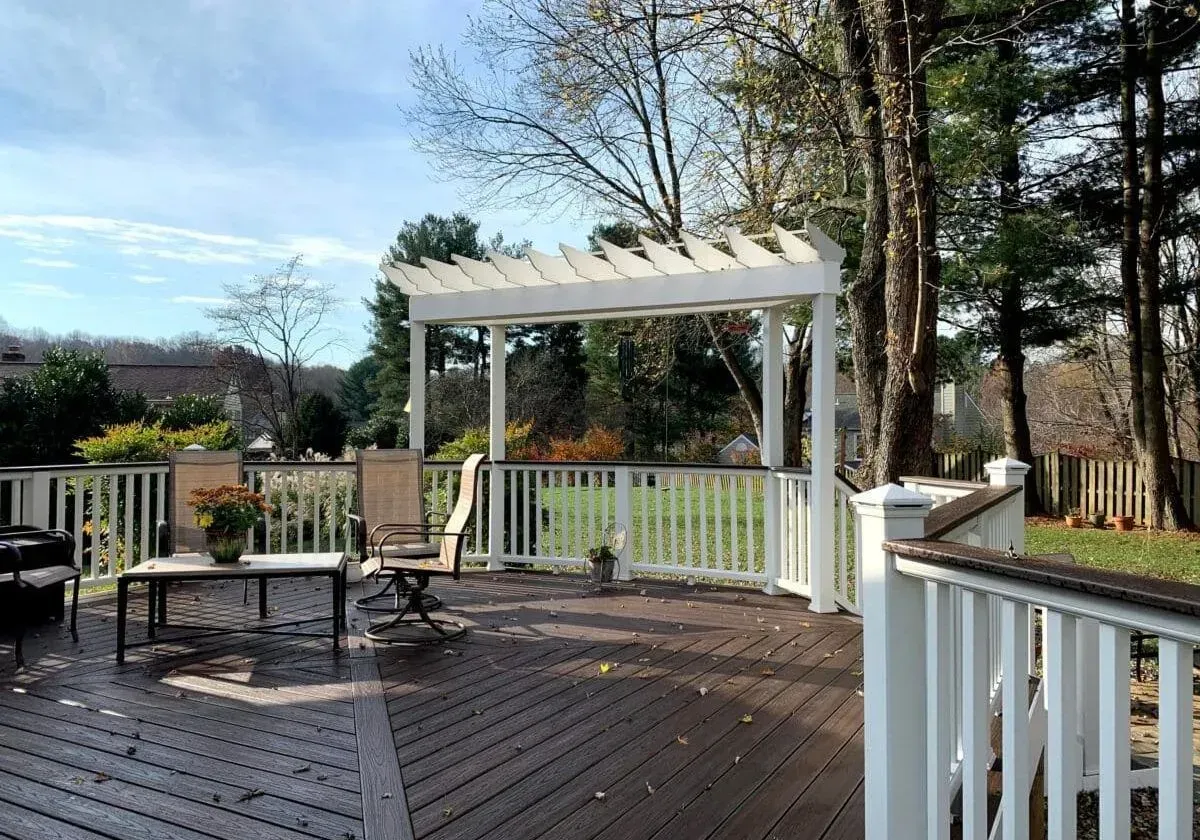 A deck with a pergola and chairs on it