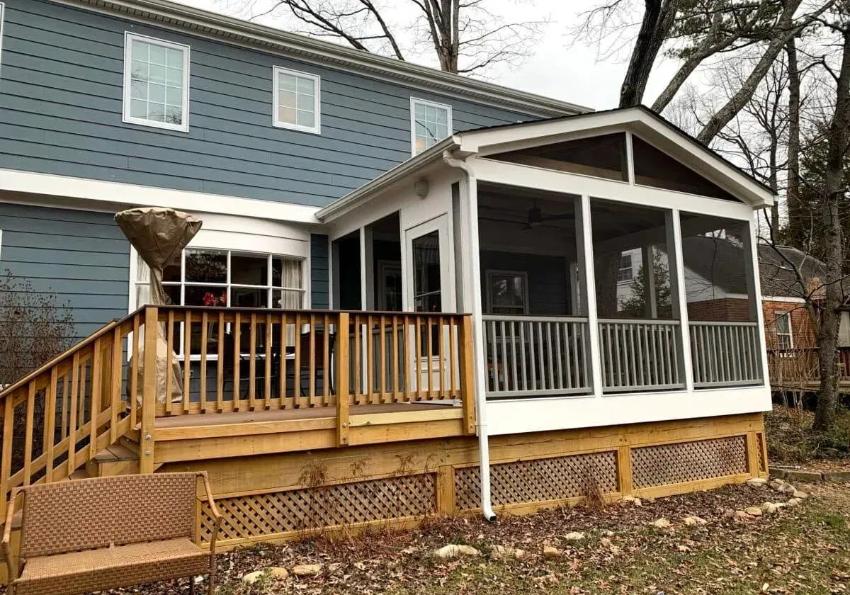 A screened in porch on the back of a house.