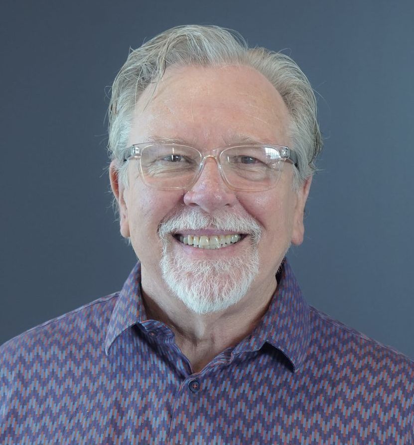 A man with glasses and a beard is smiling for the camera.