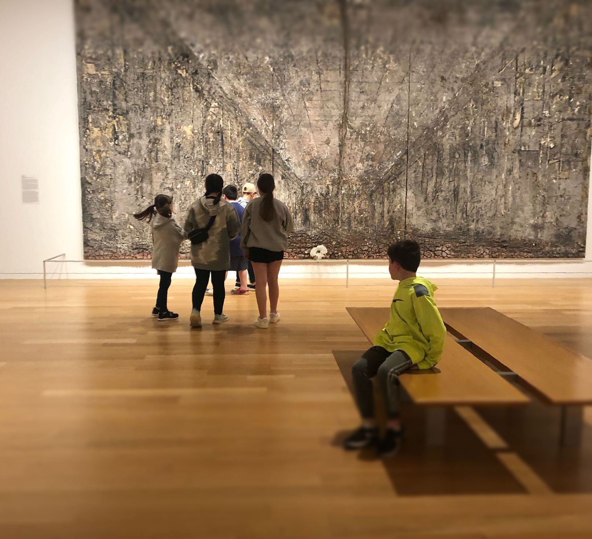 A group of people are standing in front of a large painting in a museum.