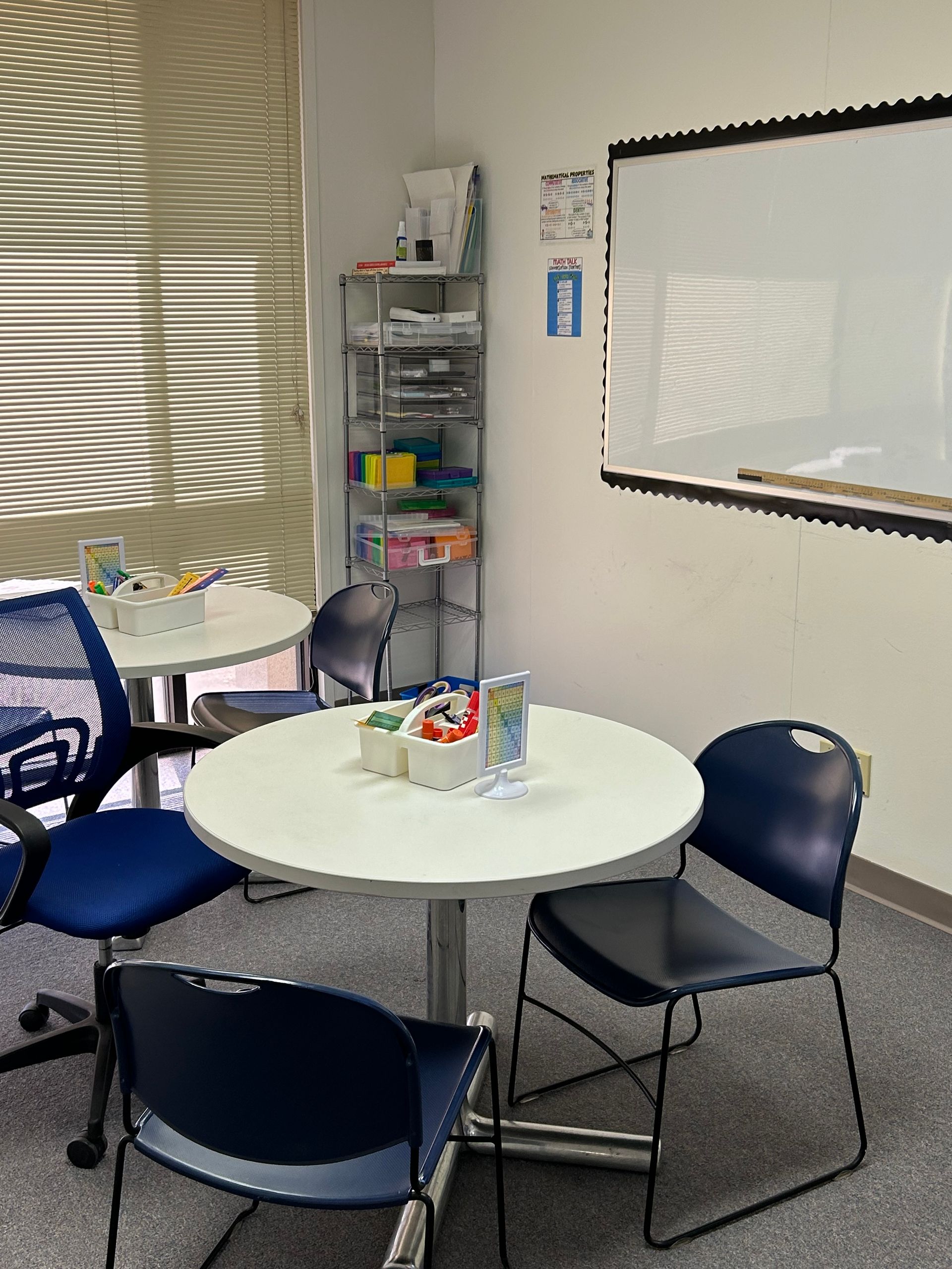 A room with tables and chairs and a white board