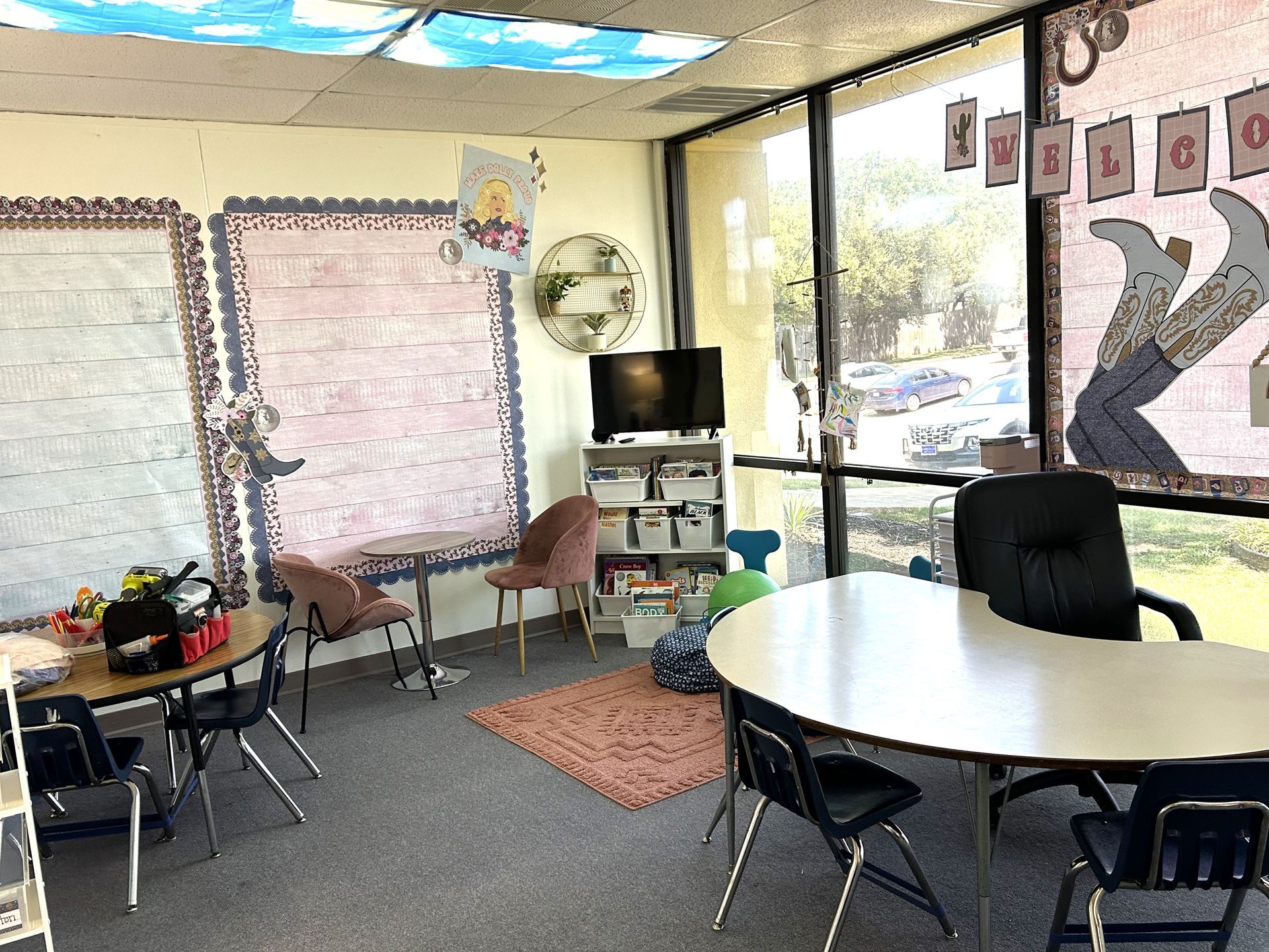 A classroom with a table , chairs , and a television.