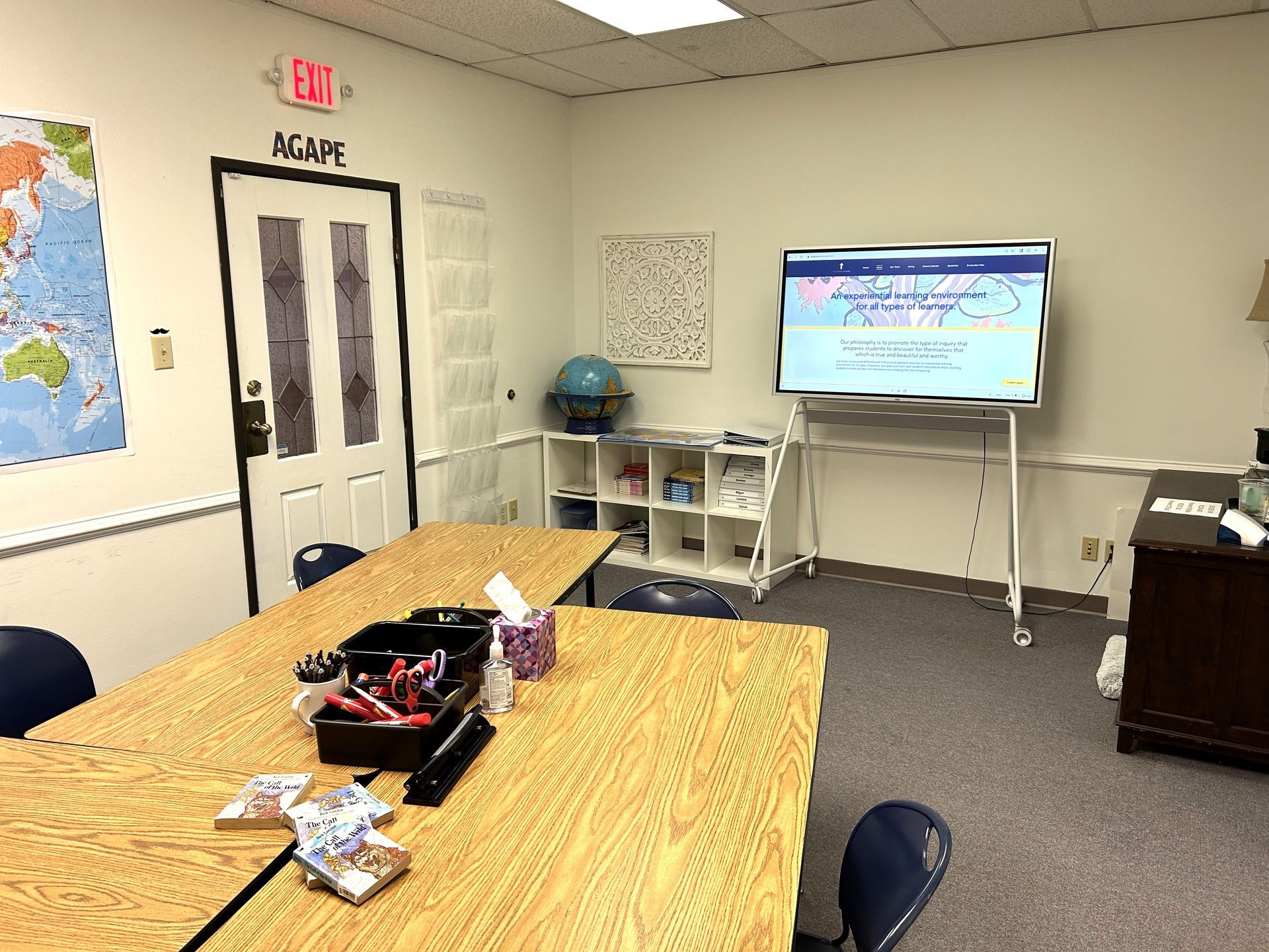 A room with a table and chairs and an exit sign on the wall