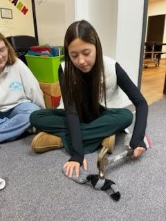 A girl is sitting on the floor playing with a stuffed animal.