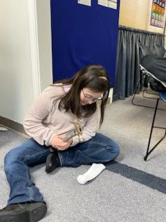 A woman is sitting on the floor with a pair of socks on her feet.