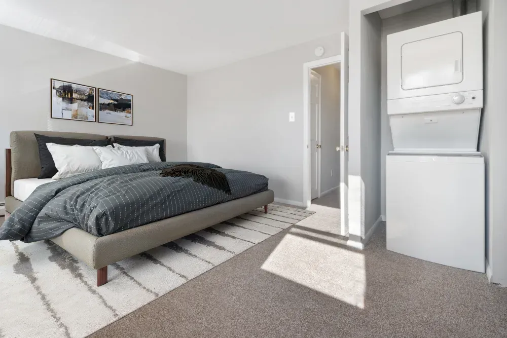 Cozy bedroom featuring a bed and stacked washer-dryer unit