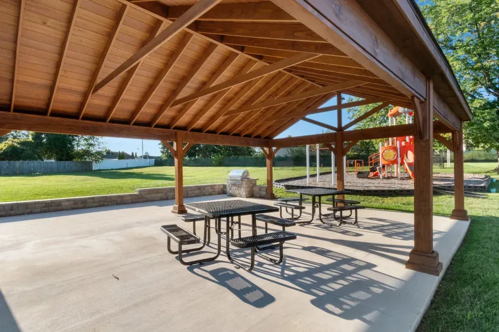 Covered picnic area with tables and playground in the background