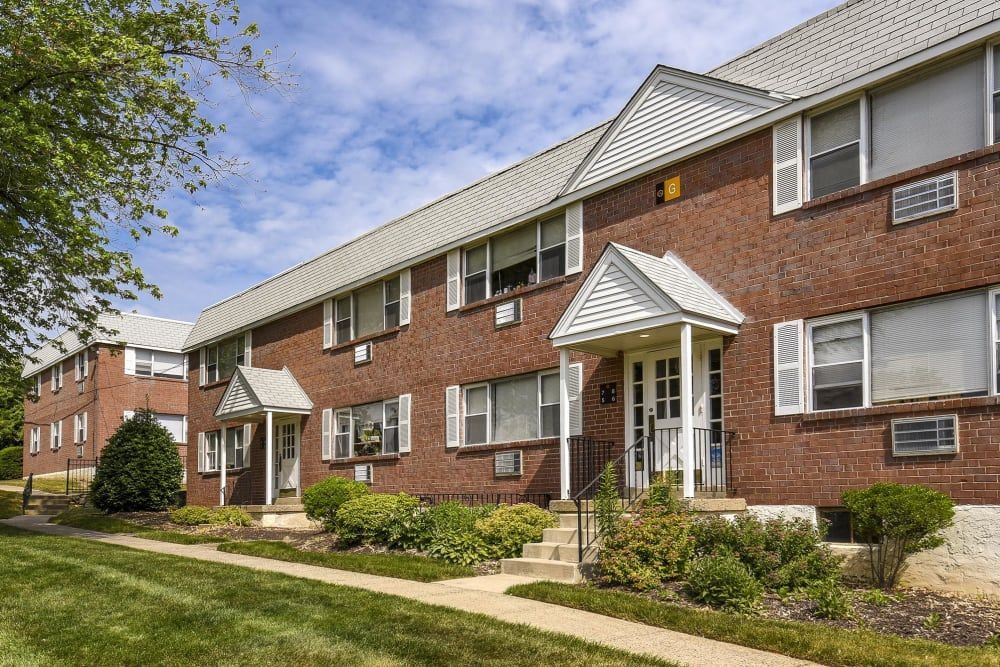 Exterior view of a two-story brick apartment building with a well-maintained entrance and landscape.