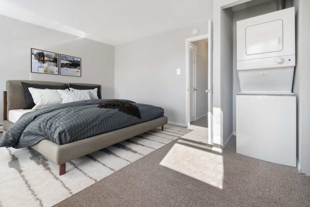 A cozy bedroom featuring a bed, artwork on the wall, and a washing machine in the corner.