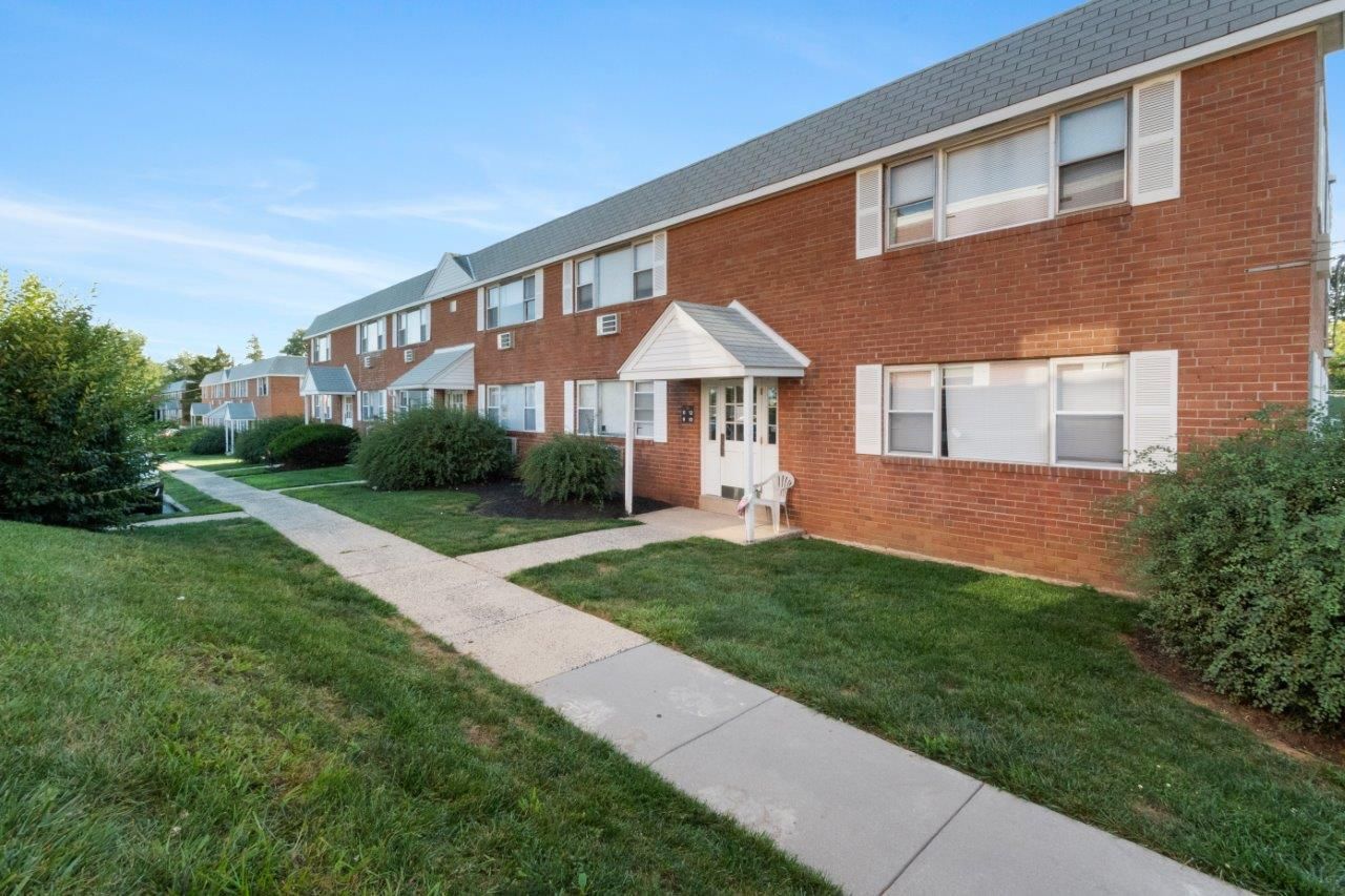 Exterior view of a brick apartment building with landscaped grounds.