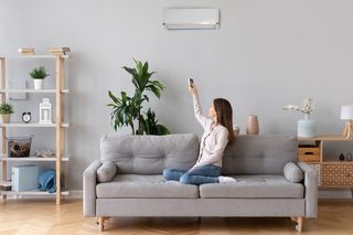 HVAC Services — Woman Switching On Air Conditioner in Alhambra, IL