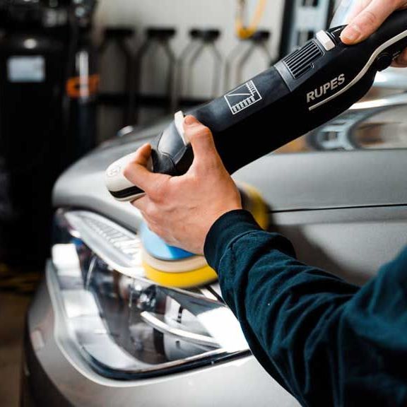 A person is polishing a car with a rupes machine