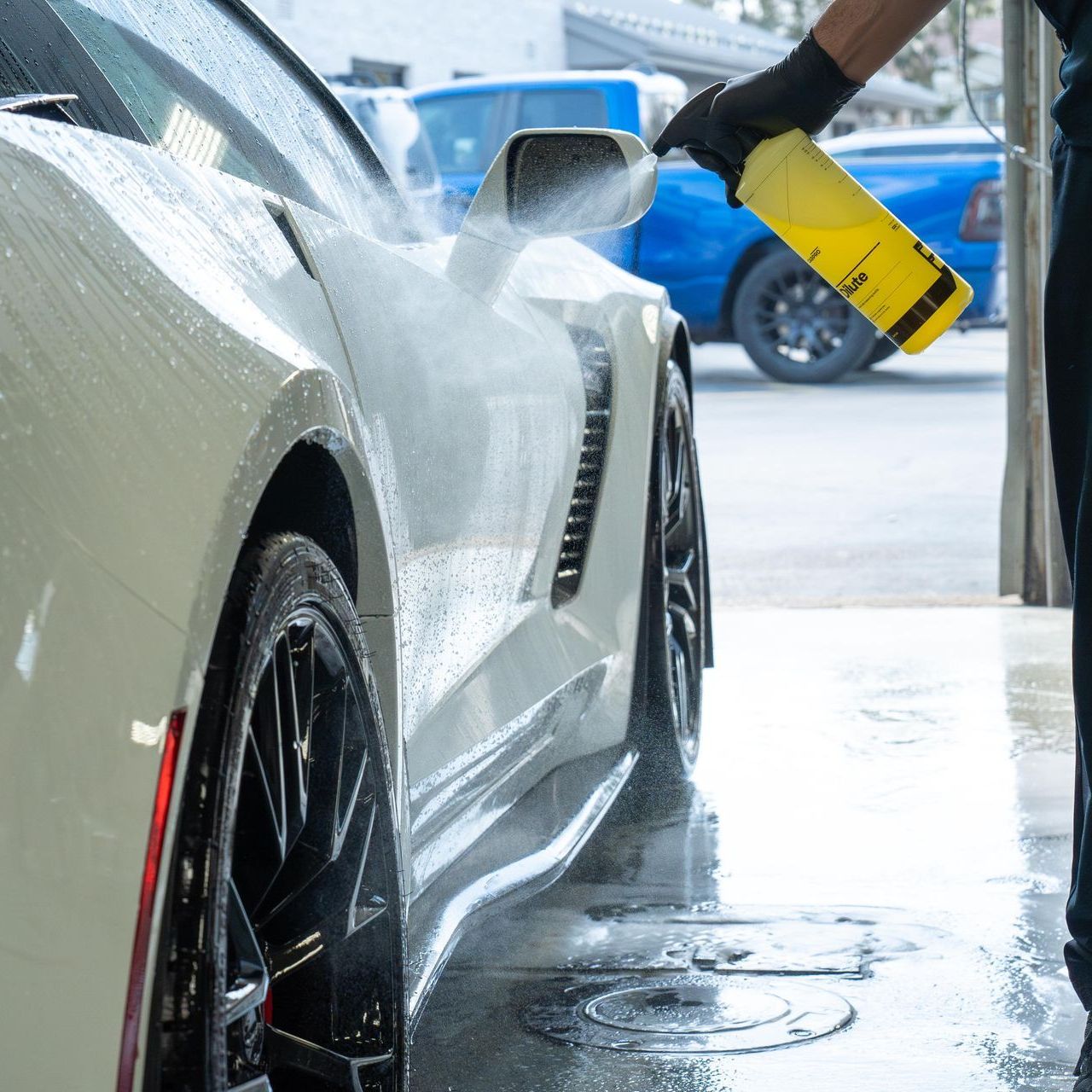 A man is spraying water on a white sports car