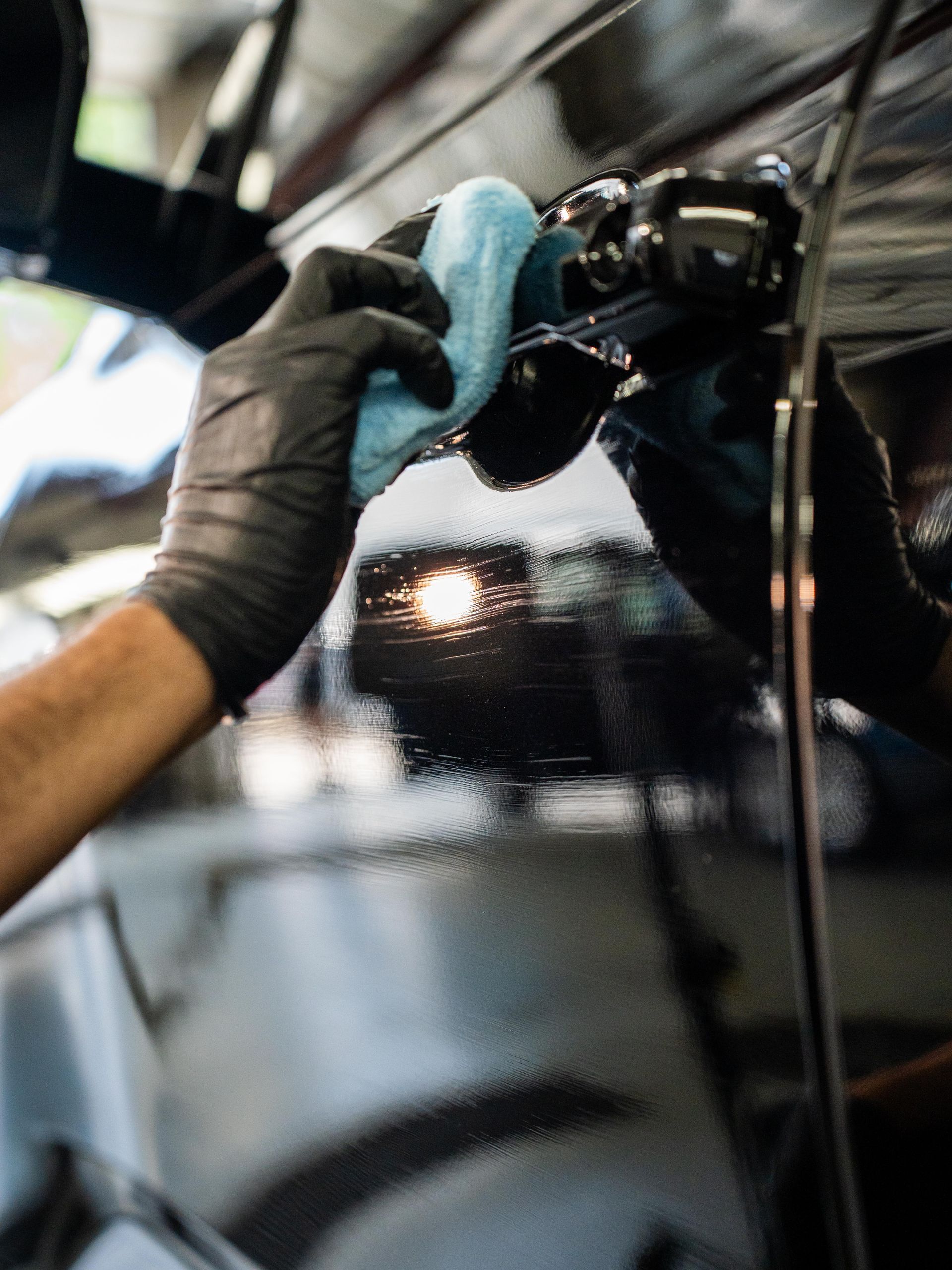 A person is polishing a car with a blue cloth.