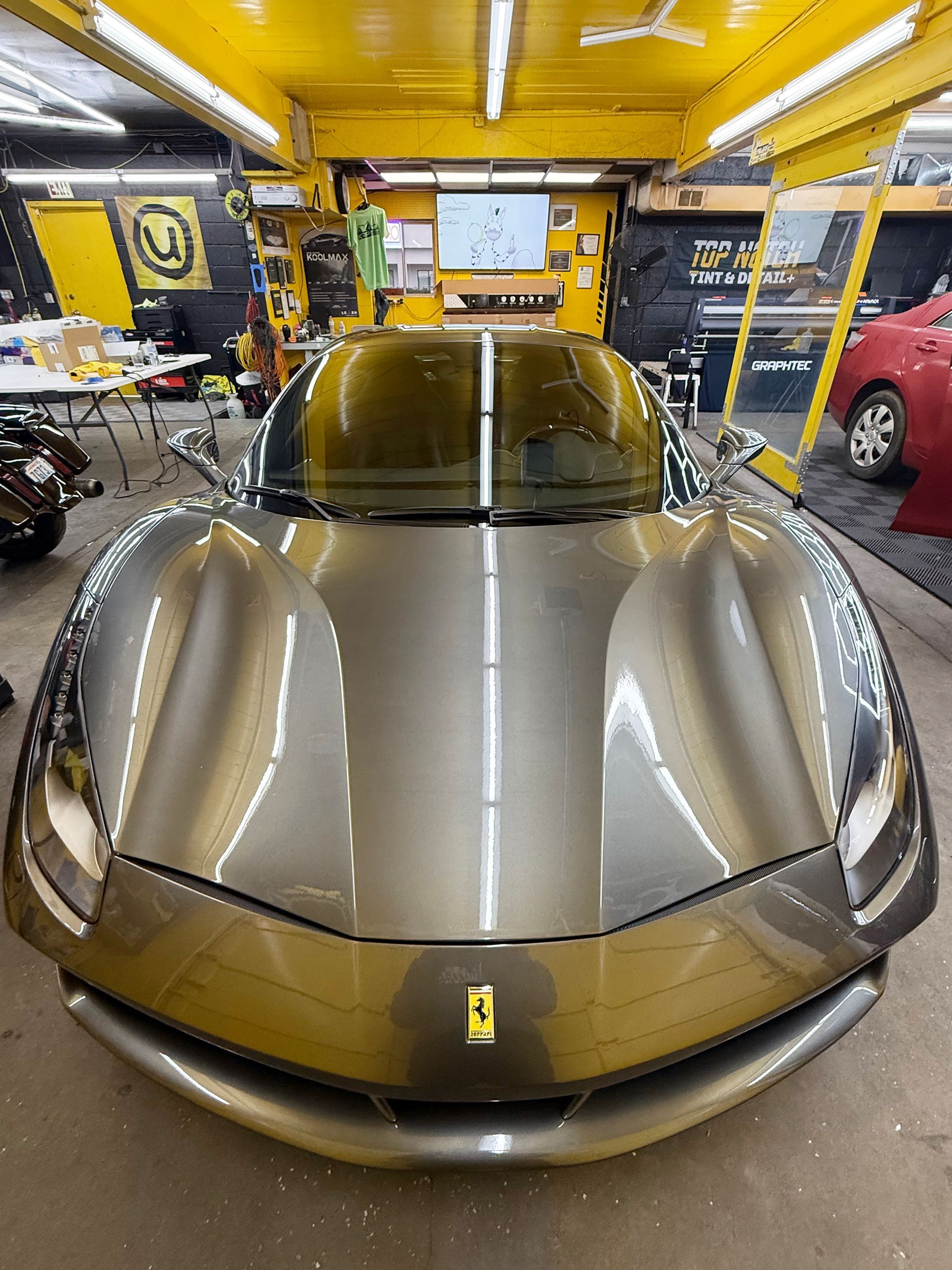 A ferrari is parked in a garage with a yellow ceiling.
