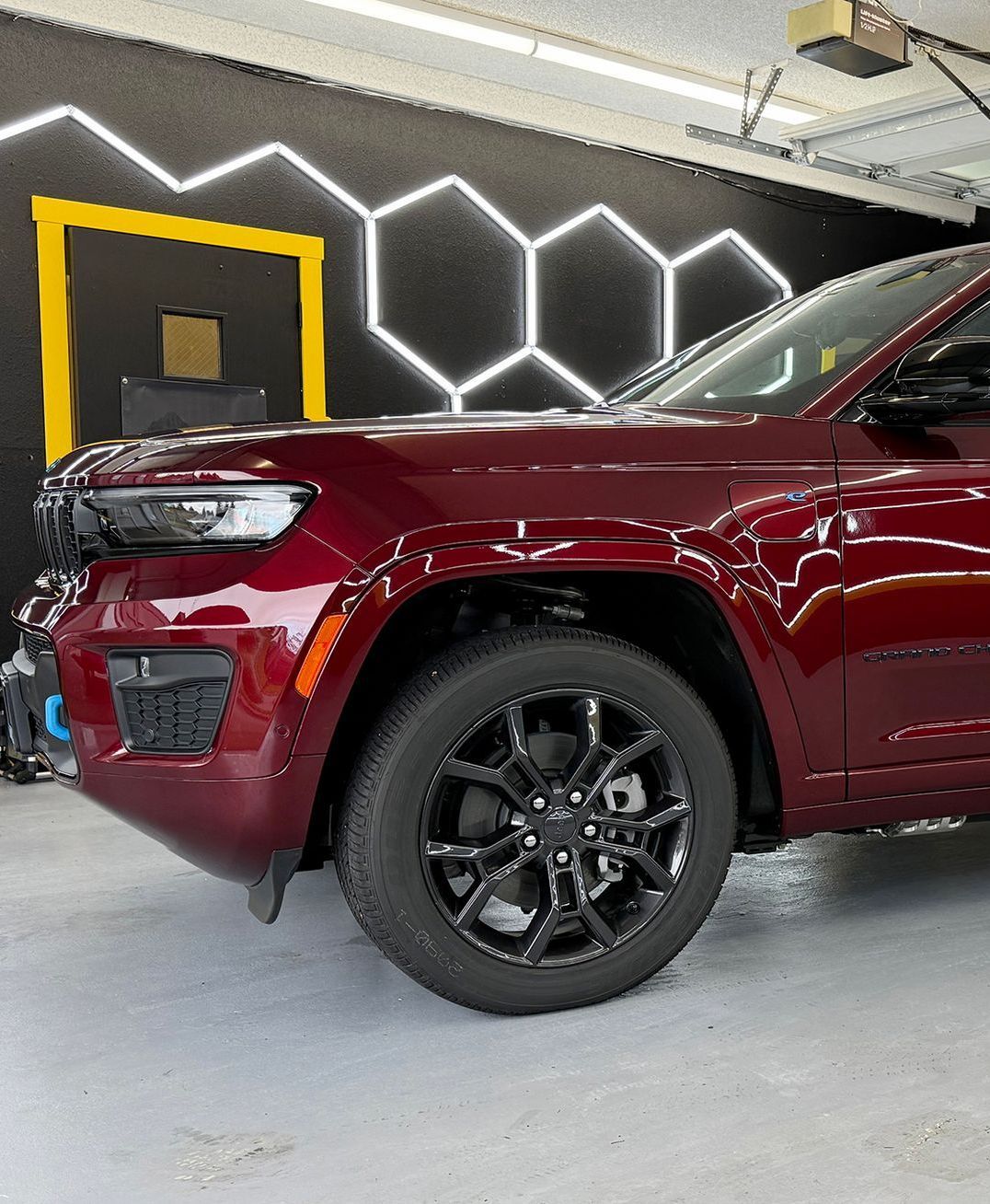 A red jeep grand cherokee is parked in a garage.