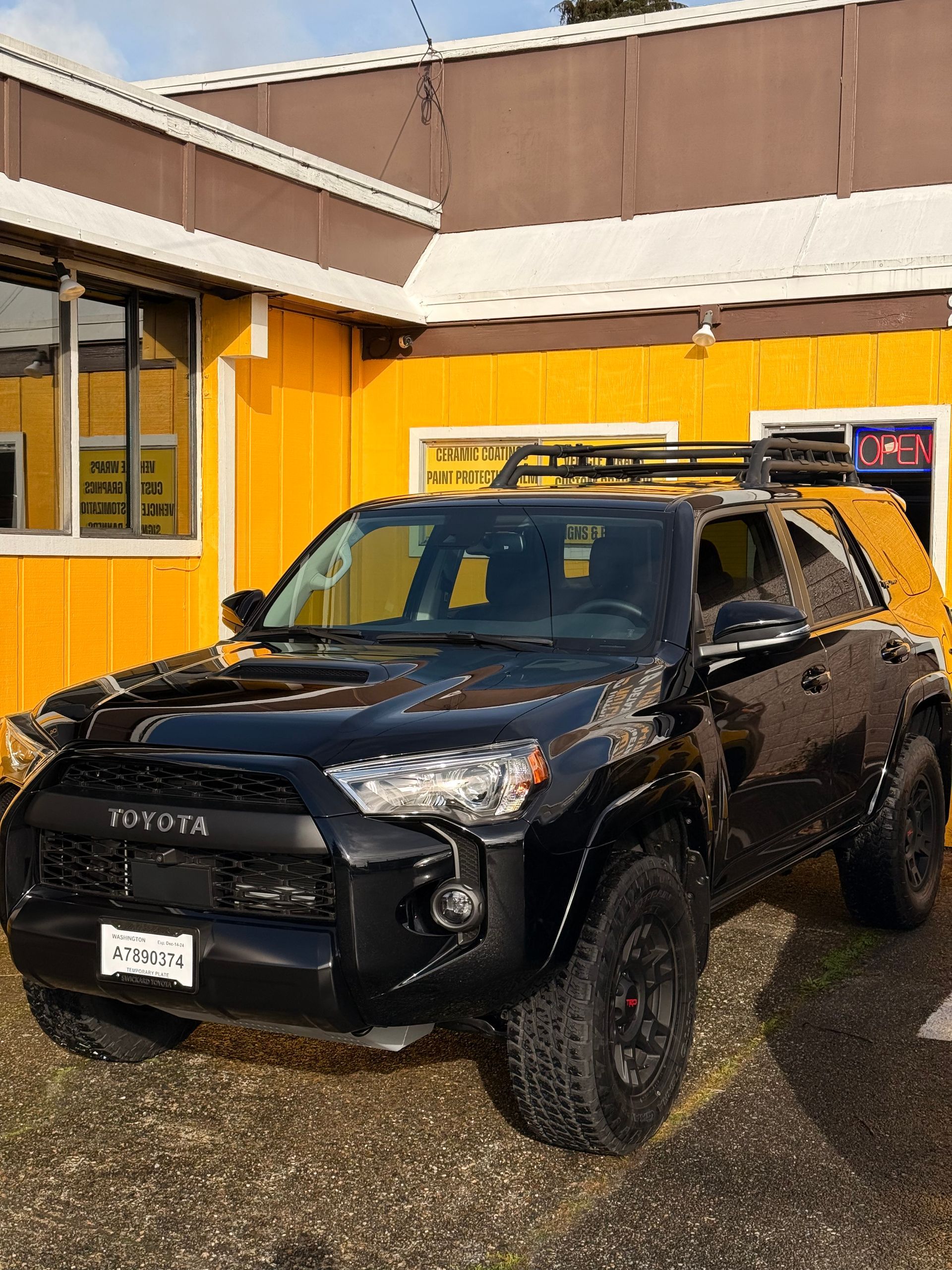 A black toyota 4runner is parked in front of the Top Notch Tint & Detail building.