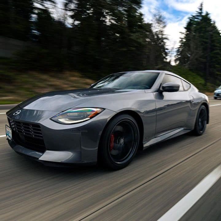 A gray sports car is driving down a highway.
