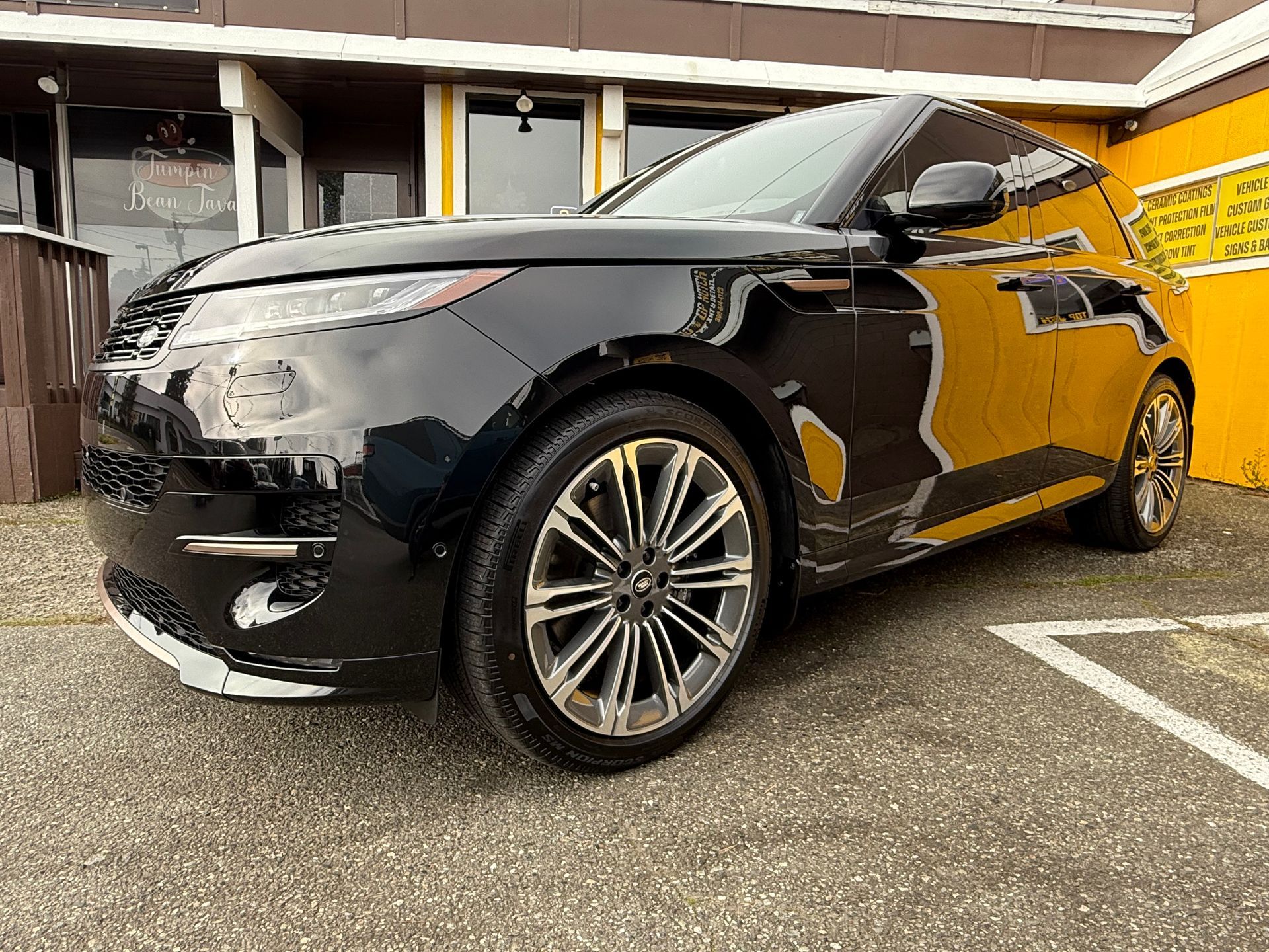 A black car is parked in a parking lot at the  Top Notch Tint & Detail  building.