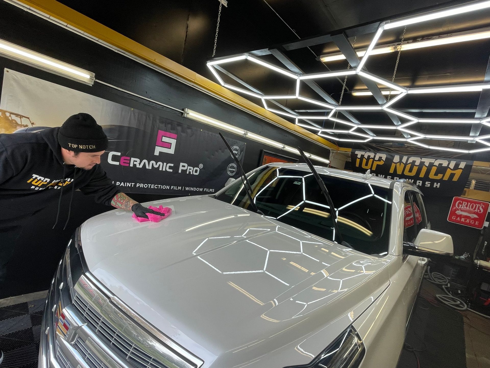 A man is cleaning the hood of a white truck in a car wash.