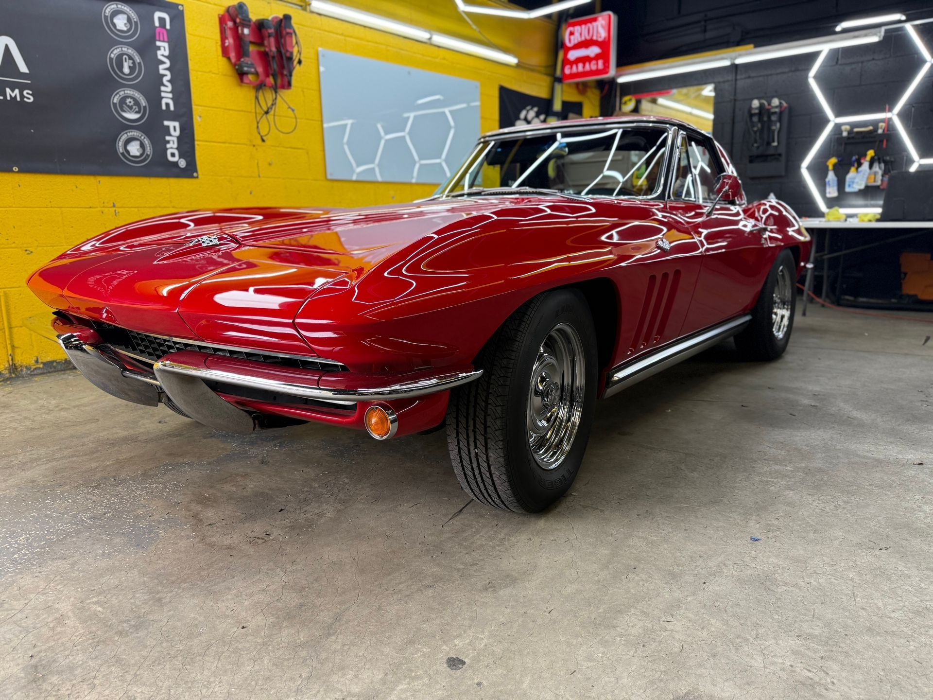 A red corvette is parked in the shop of Top Notch Tint & Detail.