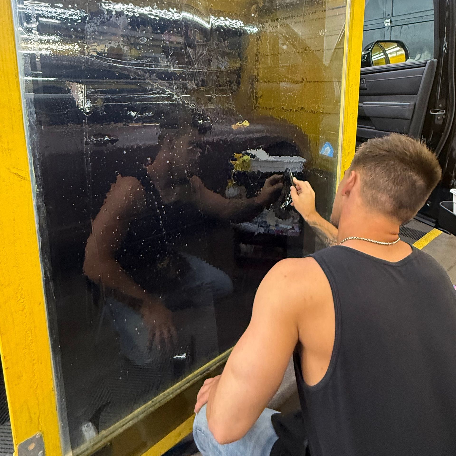 A man is preparing window tinting in a piece of glass.