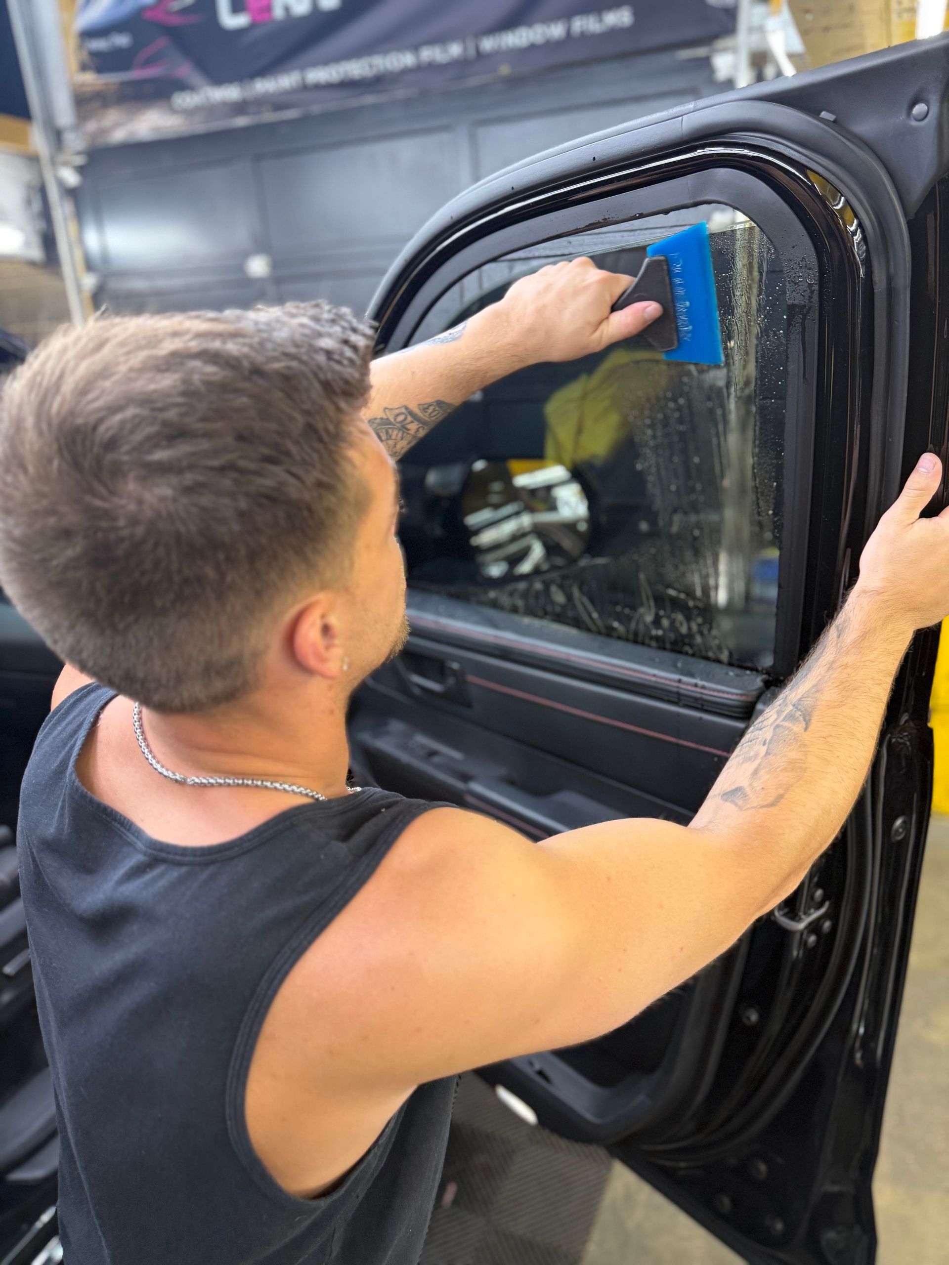 A man is applying window tinting to a car door window.