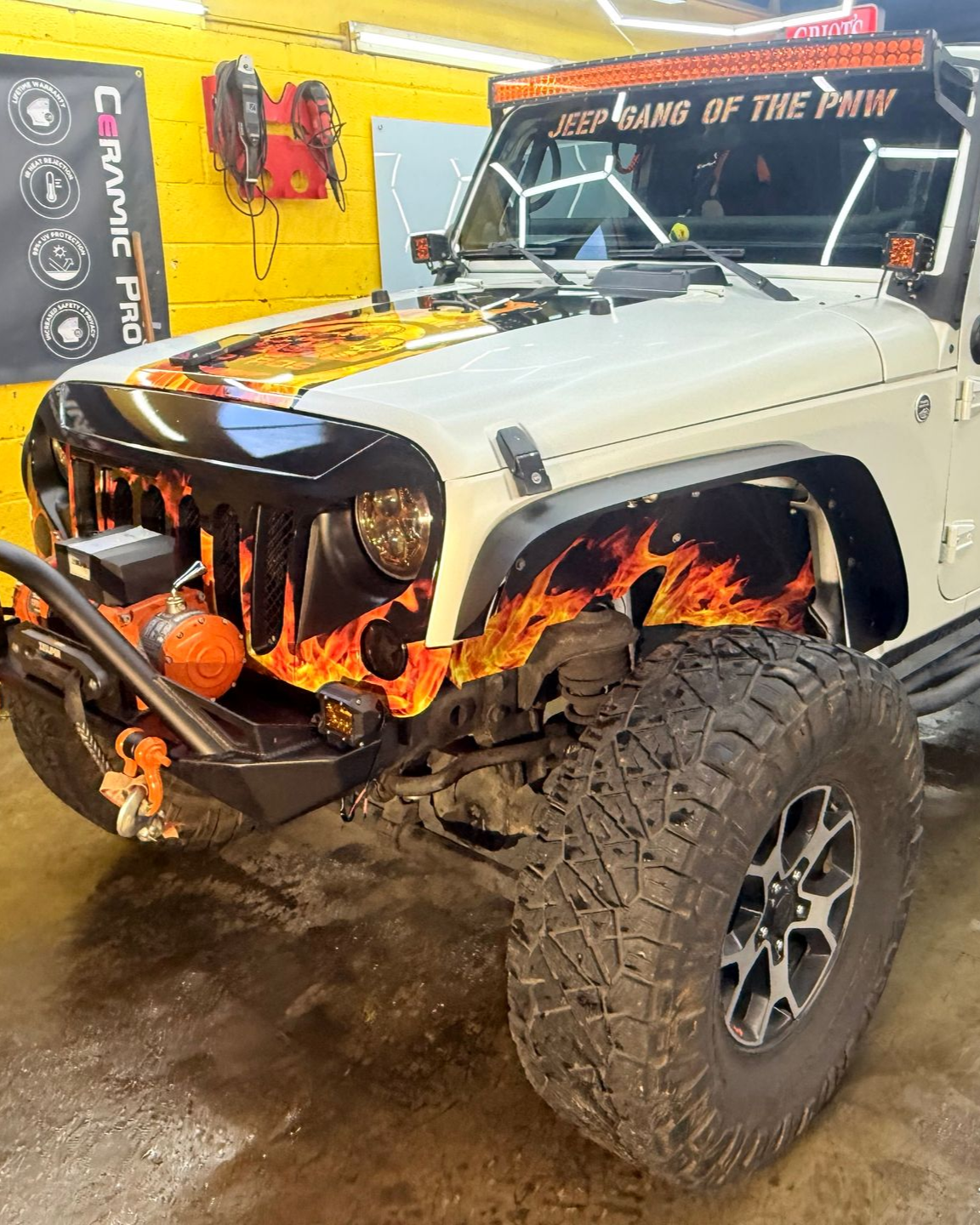 Two people wrapping a brown Bentley in a garage. One kneels, the other stands.