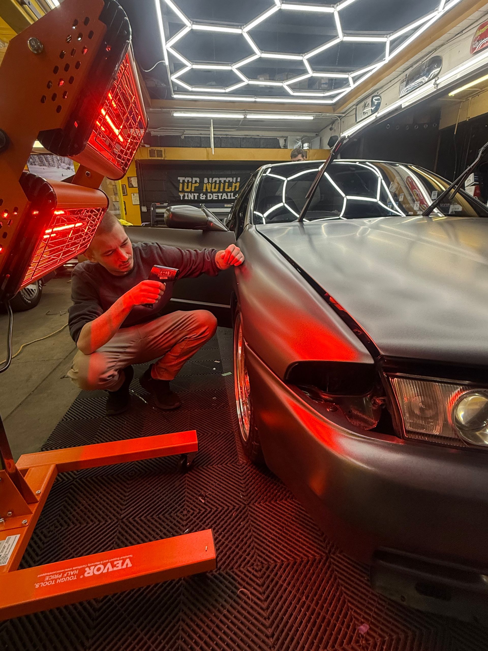A dark gray Maserati SUV parked in front of a yellow building.
