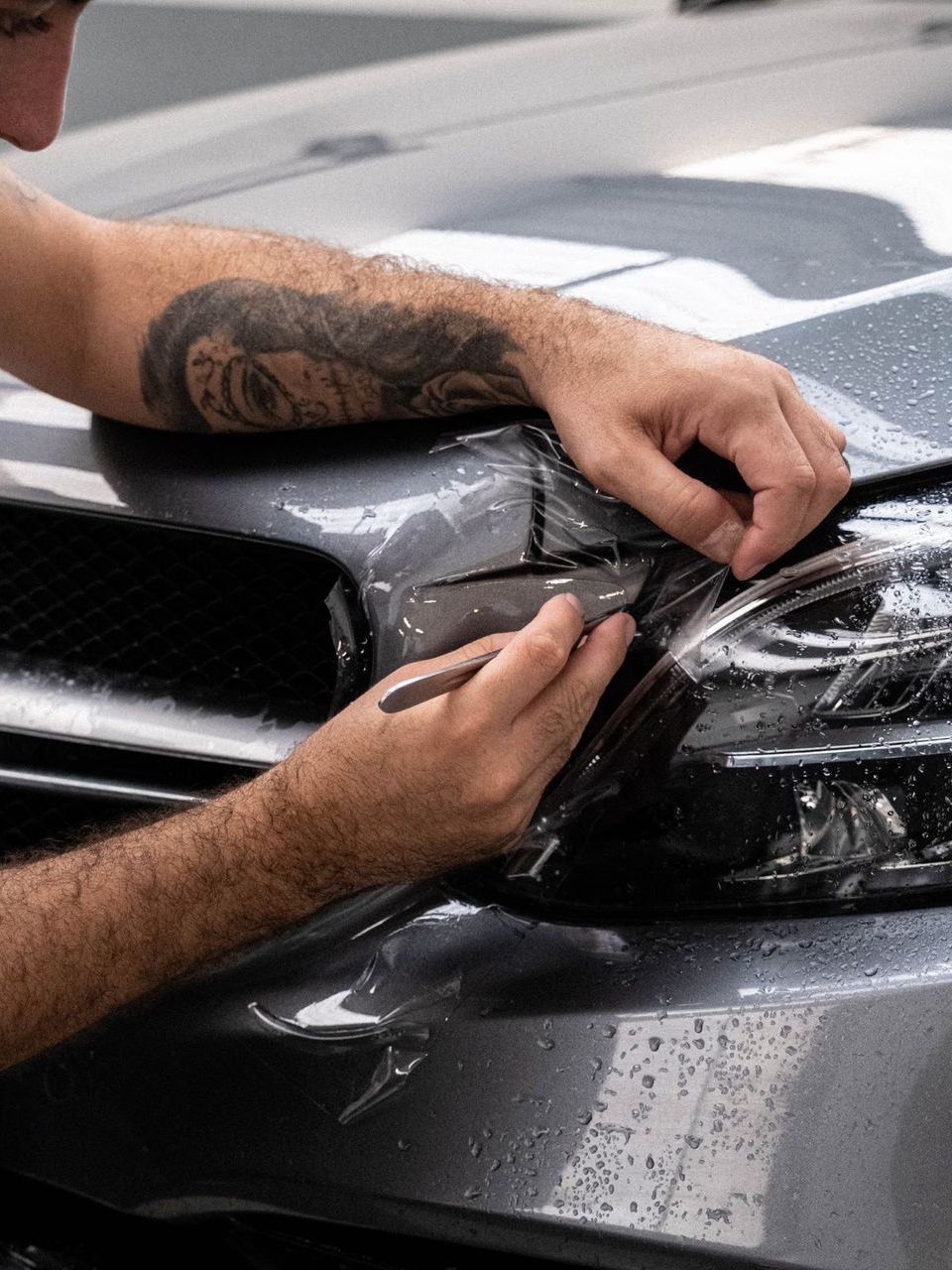 A person is cleaning a blue car with an orange towel