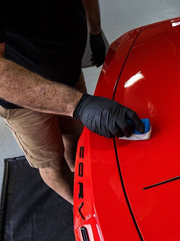 A man Wiping a Cloth To a red car
