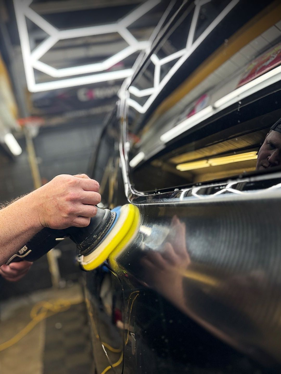 A person is polishing a car with a polisher.