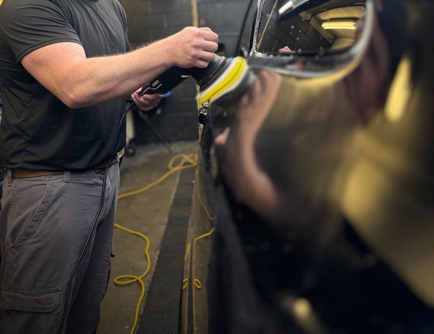 A man is polishing a car in a car wash.