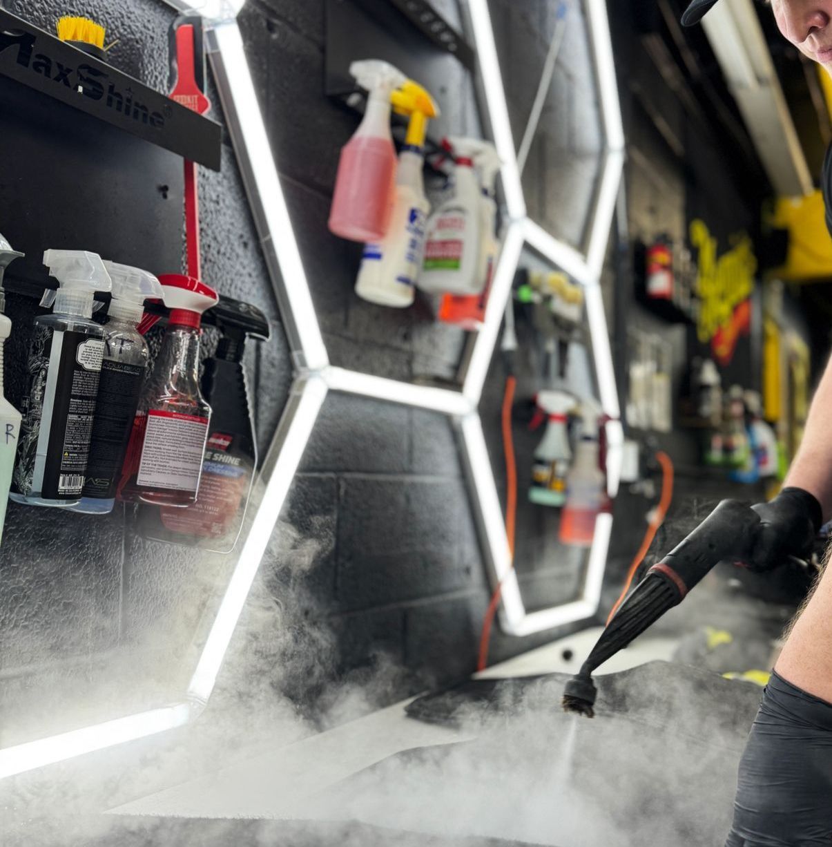 A man is using a steam cleaner to clean a car