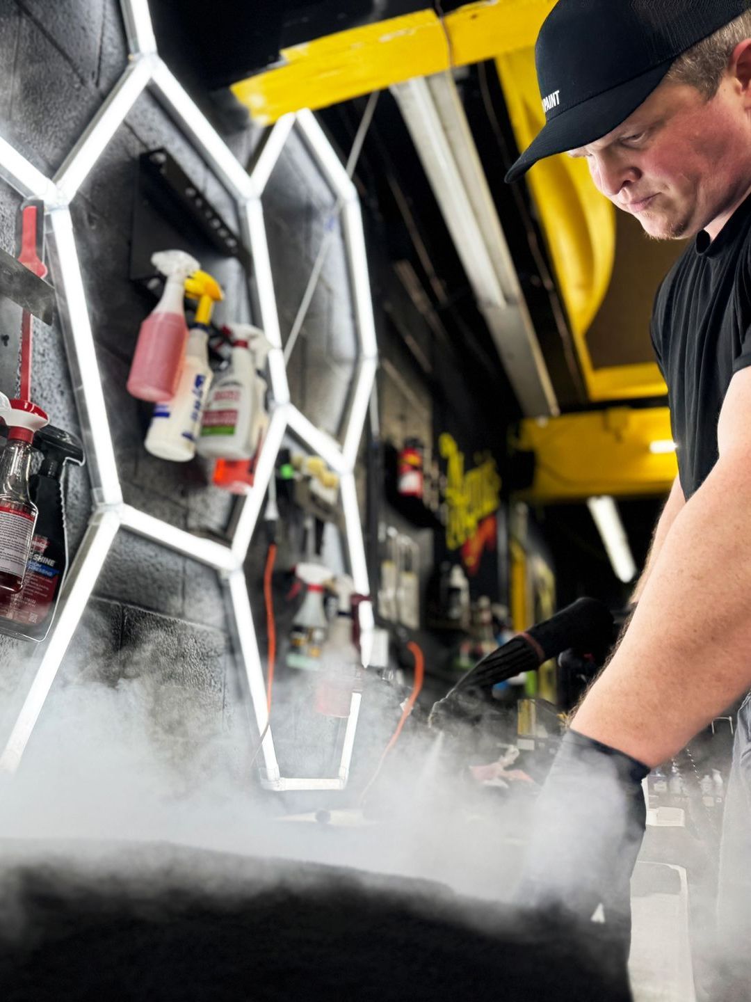 A man in a black hat is cleaning a tire with steam coming out of it.