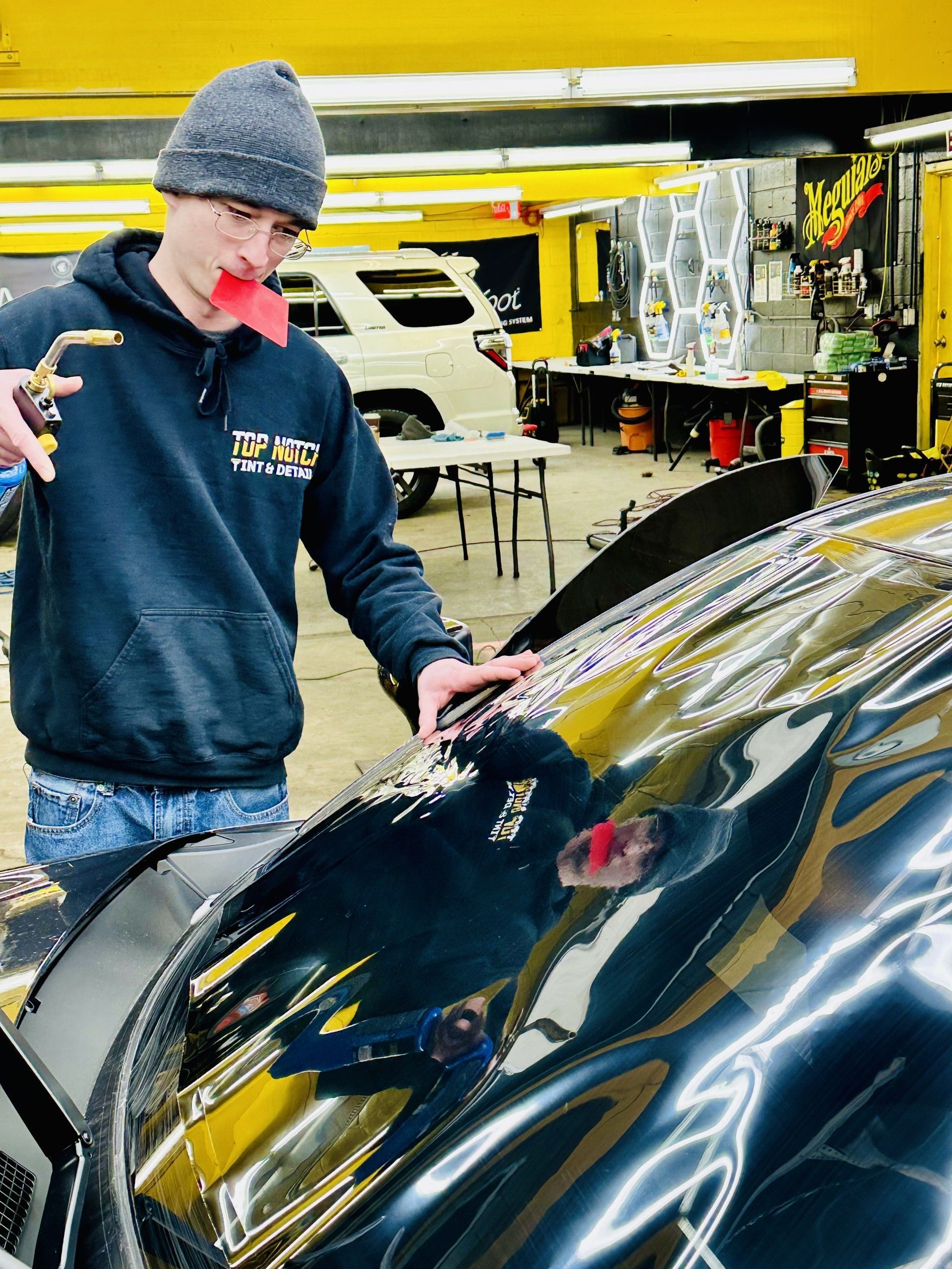 A man is standing next to a black car in a garage.