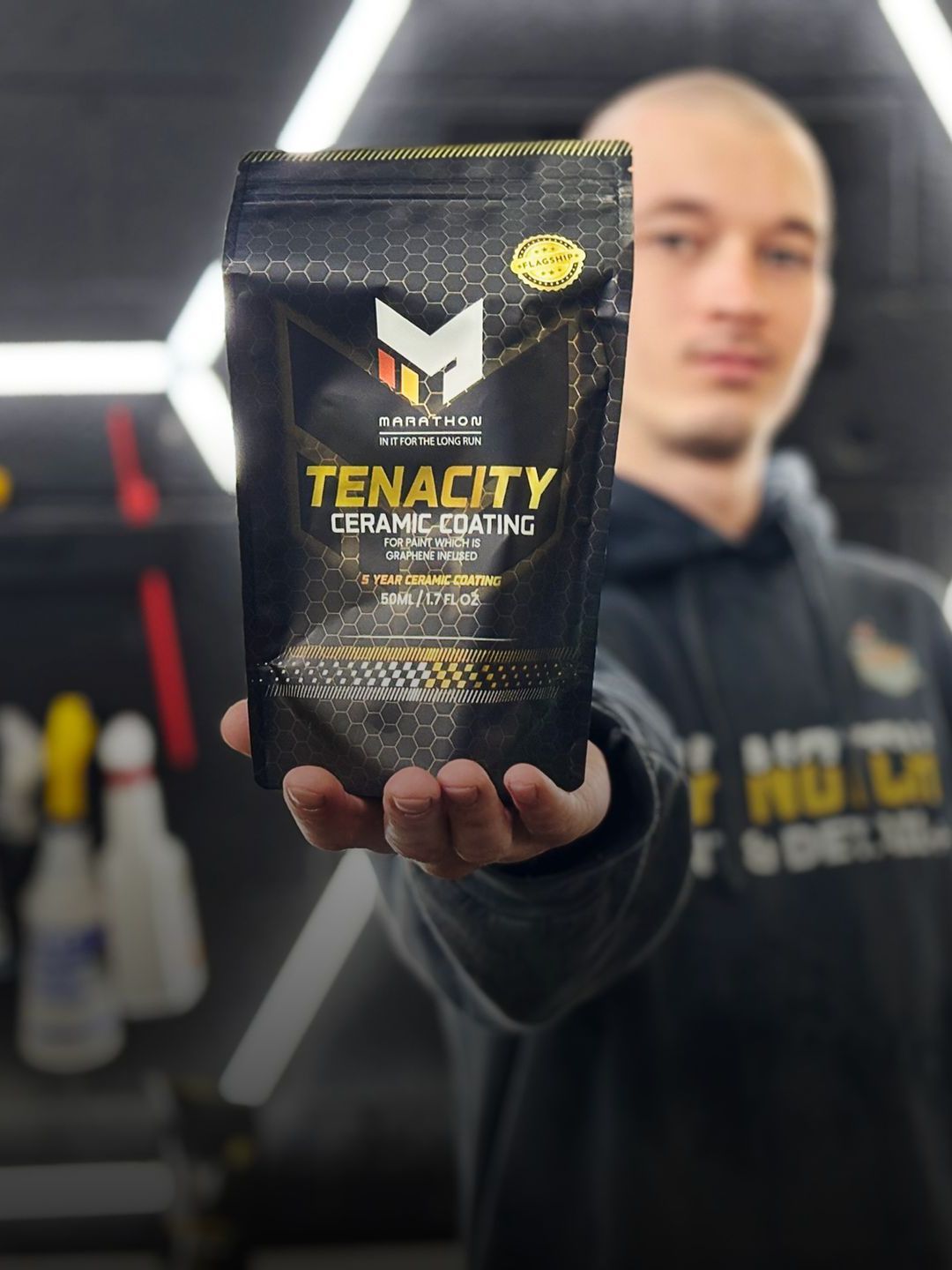 A man is holding a bag of tenacity ceramic coating